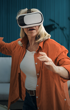 Femme mature joue à un jeu vidéo avec un casque de réalité virtuelle, semblant fascinée et pleinement engagée.