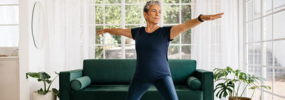 Femme mûre posant à la maison avec les bras étendus horizontalement